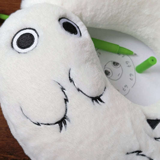 Detail of Brushbuddy neck pillow with a special seal and magic wand in the background.