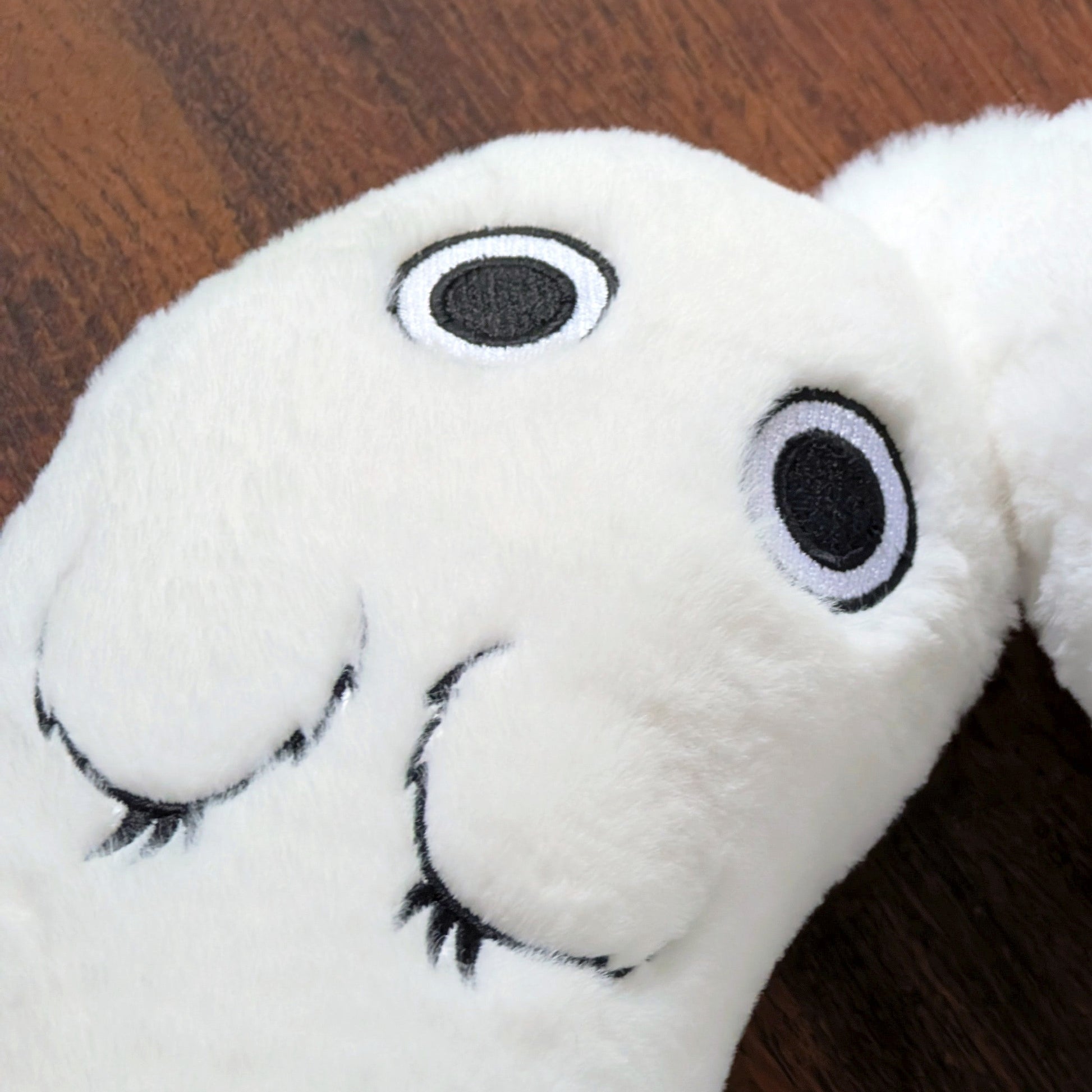 Additional close-up of Brushbuddy neck pillow showing embroidered eyes and paws.